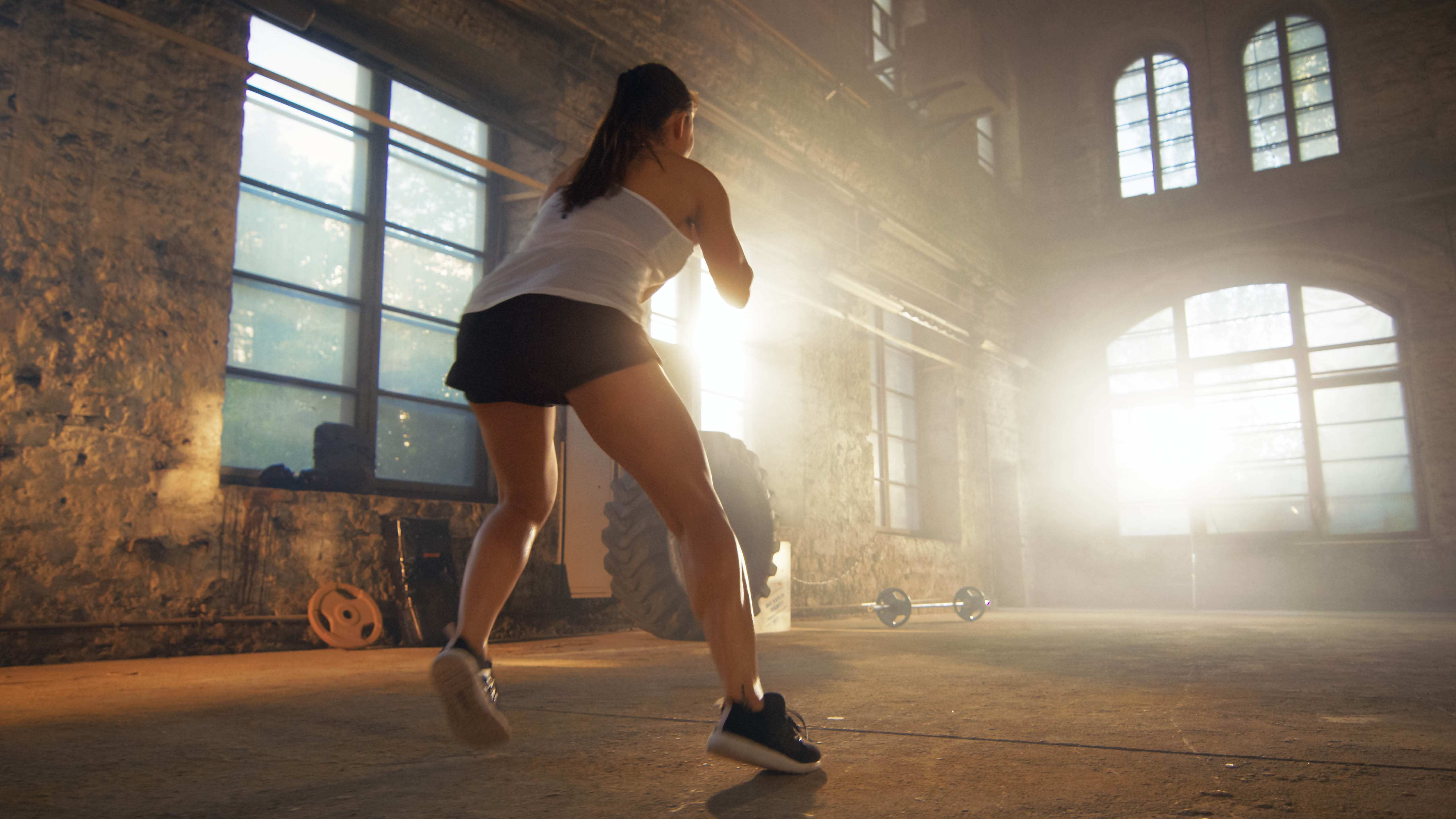 Young woman completing cardio intervals alone in a fitness studio, back is to the camera